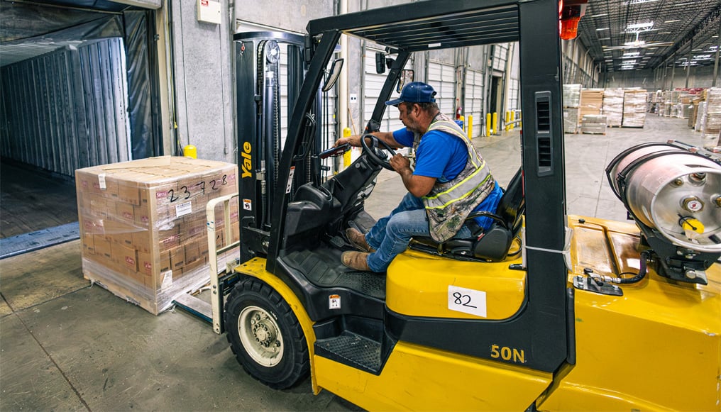 Forklift operator loading a pallet of Mexilink products into a semi-trailer for shipment.