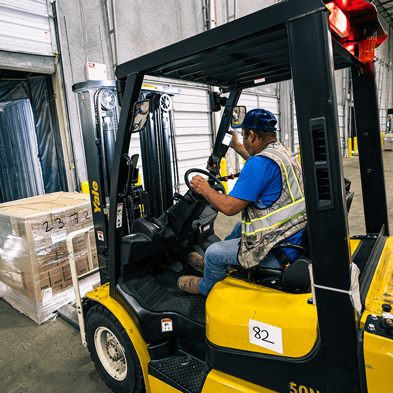 Forklift operator loading a pallet of products into a semi-trailer for shipment.