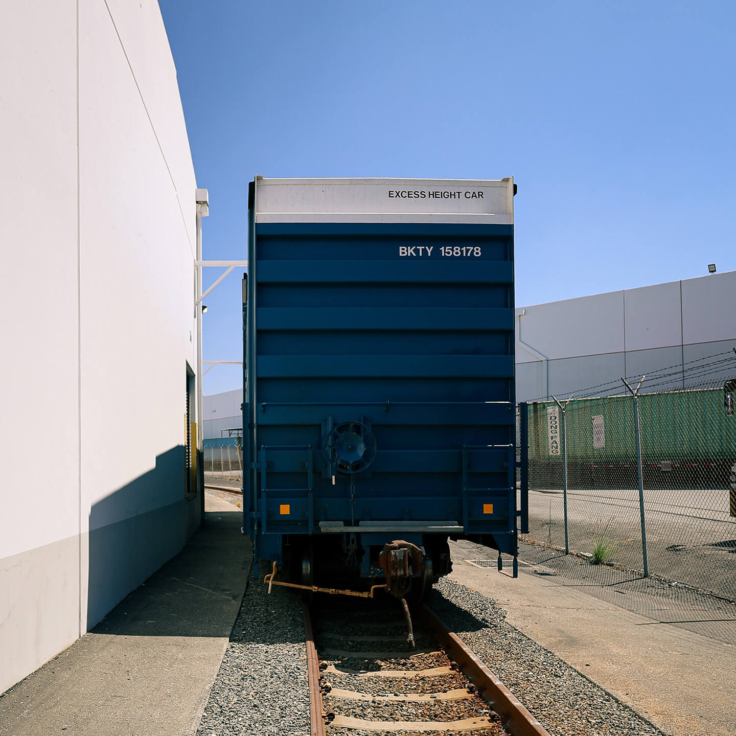 Blue rail freight boxcar parked on a track at the logistics warehouse facility.